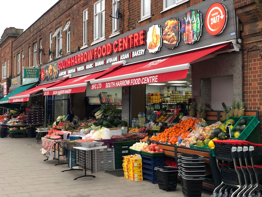 Photograph of the exterior of South Harrow Food Centre on Kingston High Street, featuring a brick building with a red and white awning displaying the store's name. The storefront has open windows show